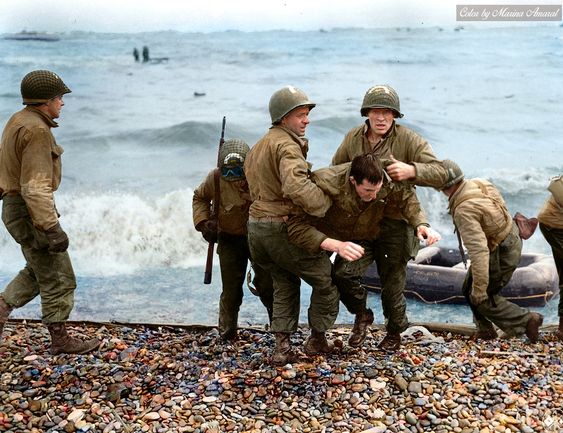 d day landing where soldiers are dragging a buddy from the water on Omaha beach.